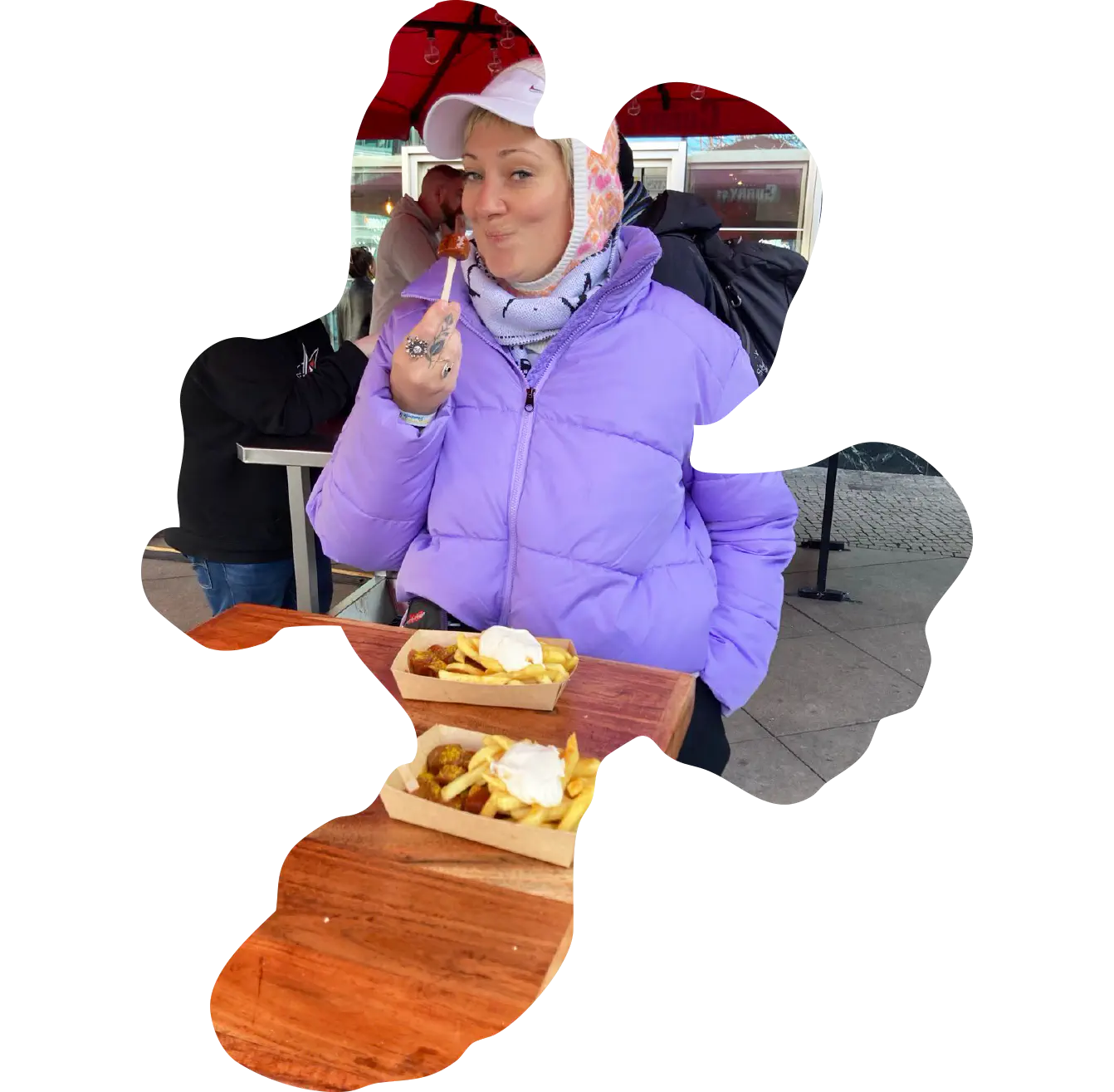 Porträt von Julia. Sie sitzt mit Winterkleidung auf einer Bierbank und ist Pommes.