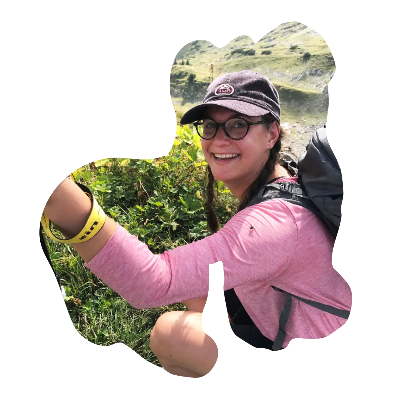 Porträt von Tosca. Sie steht lachen mit einem Wanderrucksack und Cap in der Natur.